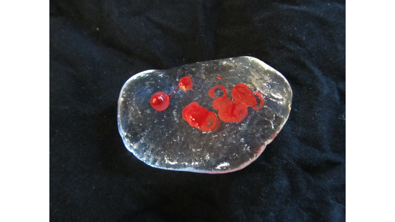 A piece of melted InstaMorph moldable plastic shown with some epoxy gel coloring in red not hand molded in yet.